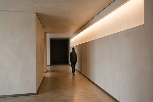 A minimalist architectural interior where light emanates directly from a cove in the wall, with no visible fixture.